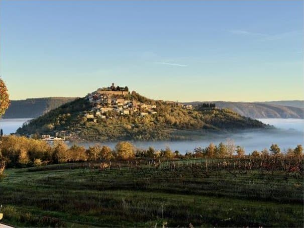 Hilltop village above misty vineyards in Istria